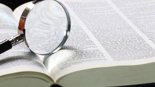 dictionary with a magnifying glass on the page