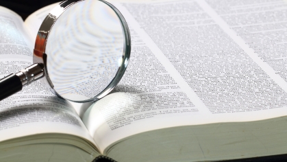 dictionary with a magnifying glass on the page