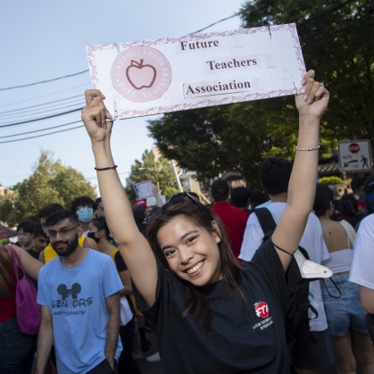 Student raises Future Teachers Association sign over her head during Rutgers involvement fair.