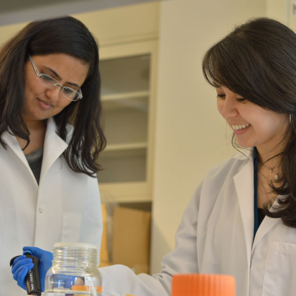 Two students in labcoats conduct experiments 