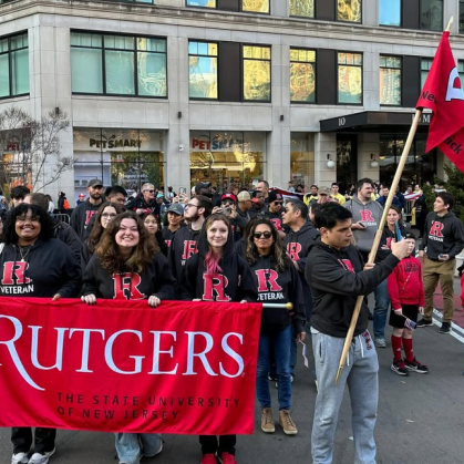 Veteran students stand in front of Rutgers Banner at the RU-N office of Veteran Affairs.