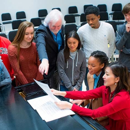 Students stand around piano during Byrne Seminar. 