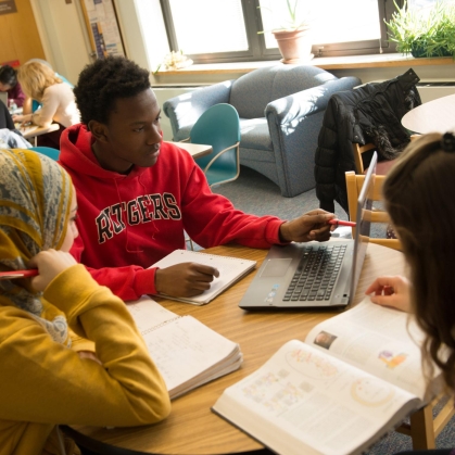 Three students sitting around a table studying.