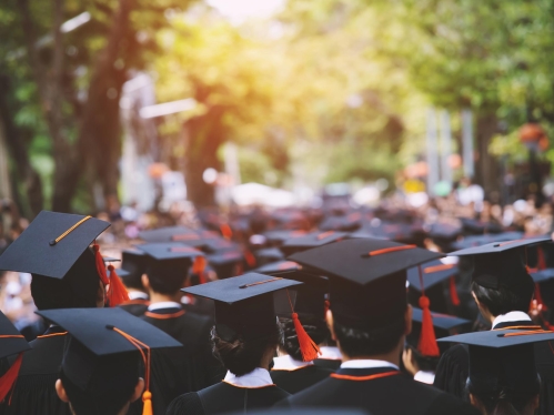 Photo of back of students walking in graduation regalia