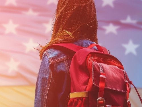 girl wearing backpack with US flag in background