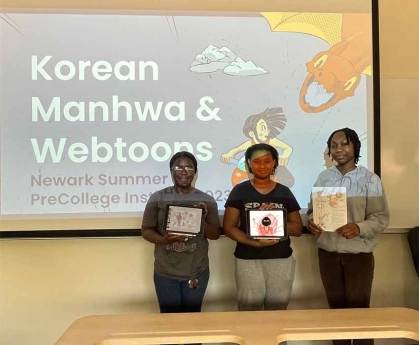 Three students in front of classroom, each holding a book